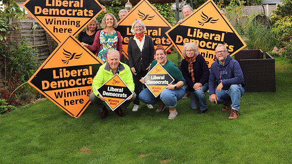 Group of people in a garden with Lib Dem Plackards
